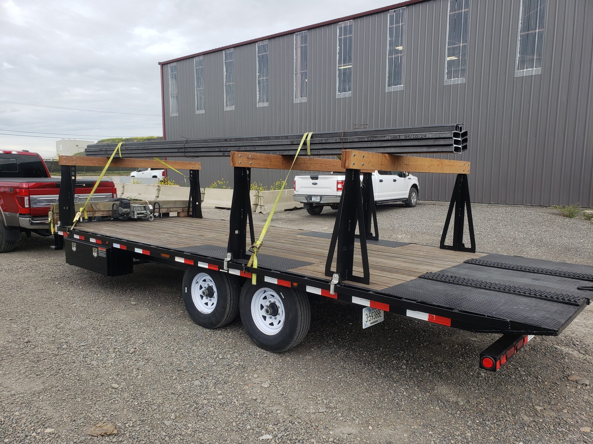 A flatbed trailer carrying large pipes parked outdoors.