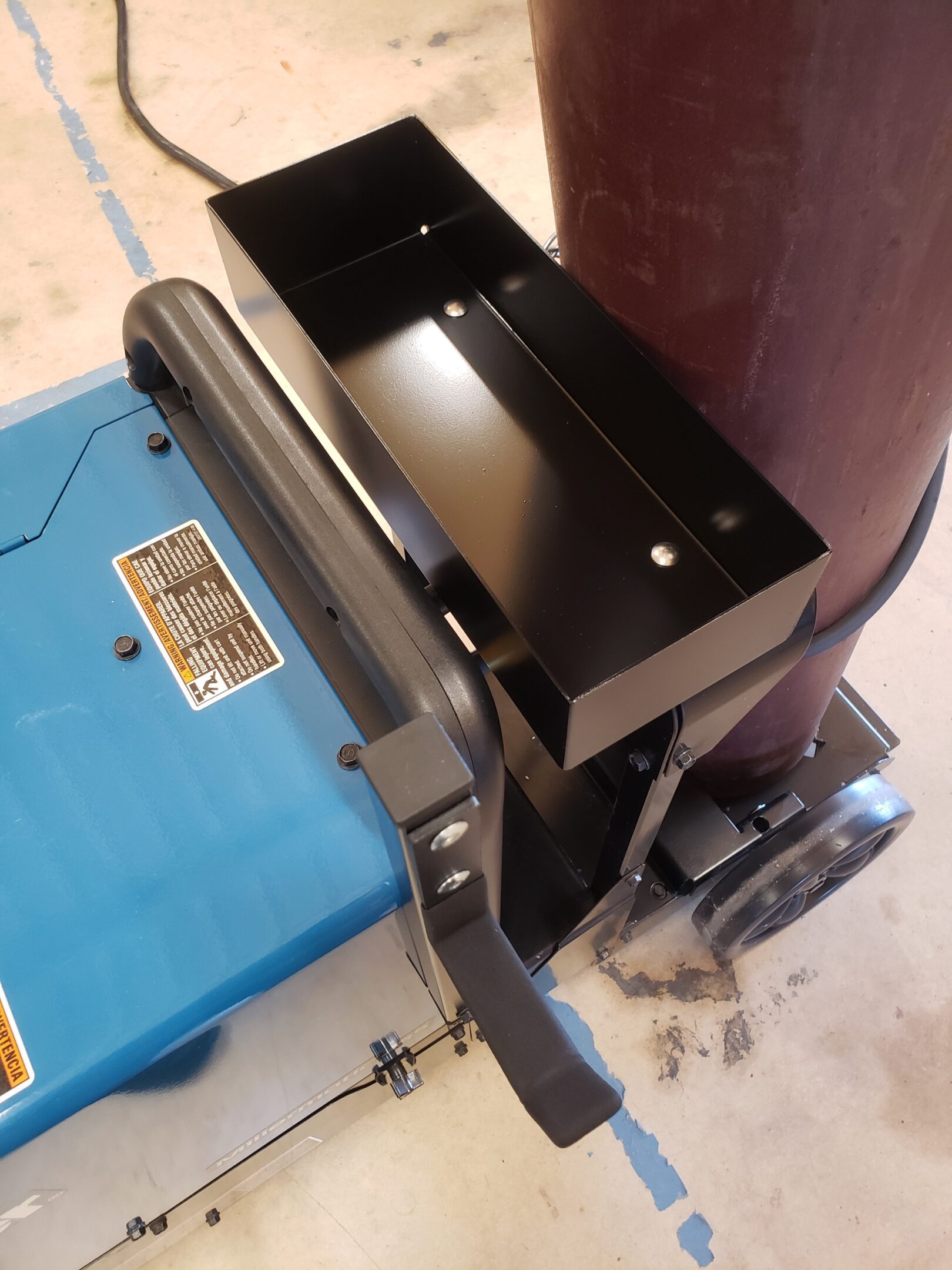 Close-up of a mechanical or electronic device with a black metal bracket and a blue case.