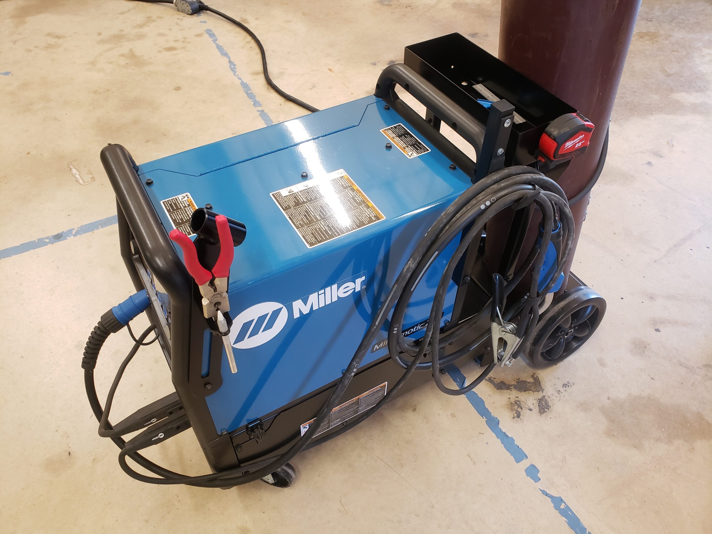 A blue Miller welding machine with cables and attachments.