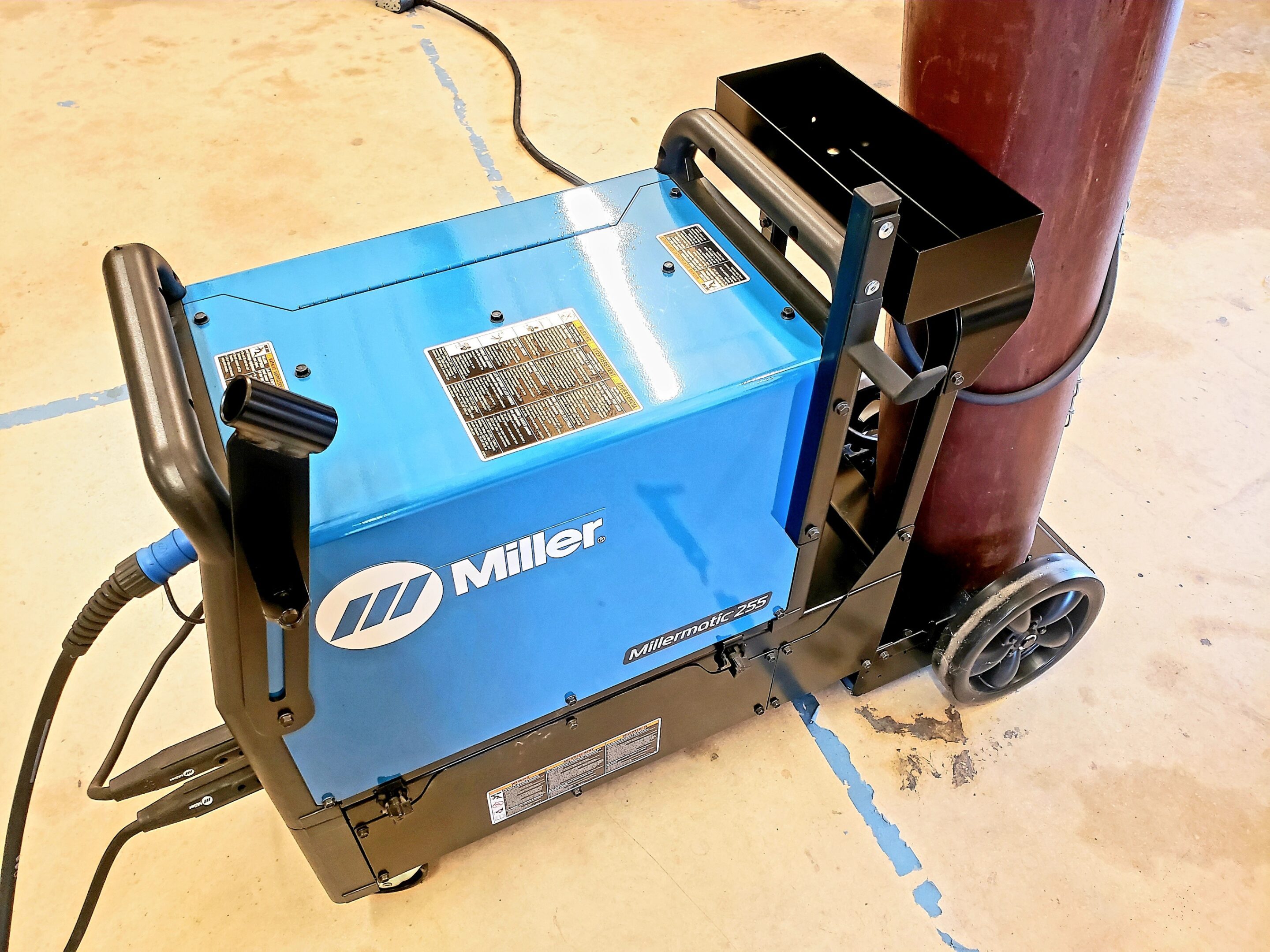 A blue Miller welding machine on wheels.